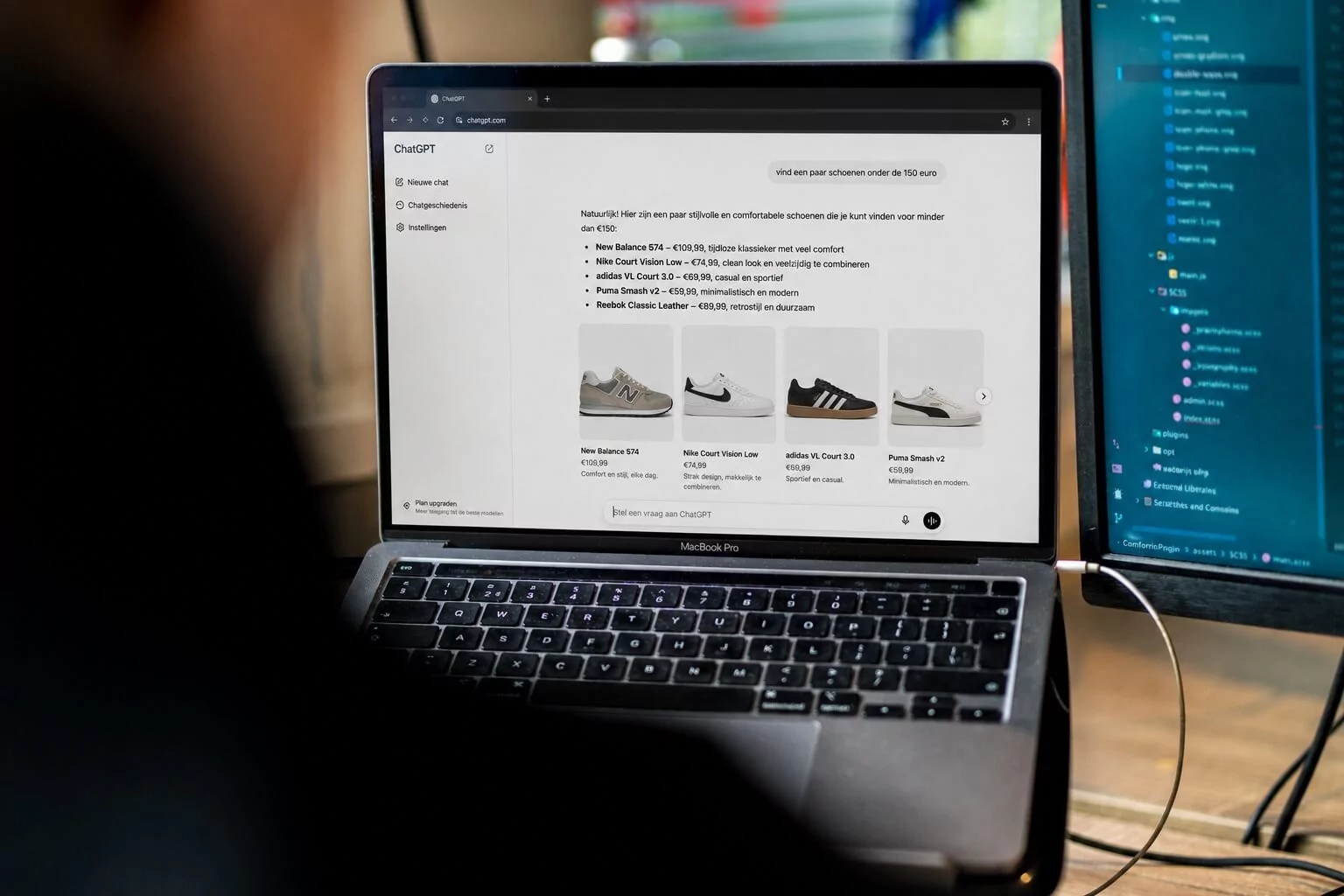 Iemand bekijkt op een laptop een website over sneakers, waarop afbeeldingen en beschrijvingen van verschillende schoenen – geoptimaliseerd met effectieve SEO-technieken – op het scherm worden weergegeven. Naast de laptop is een monitor te zien waarop een chatprogramma draait.